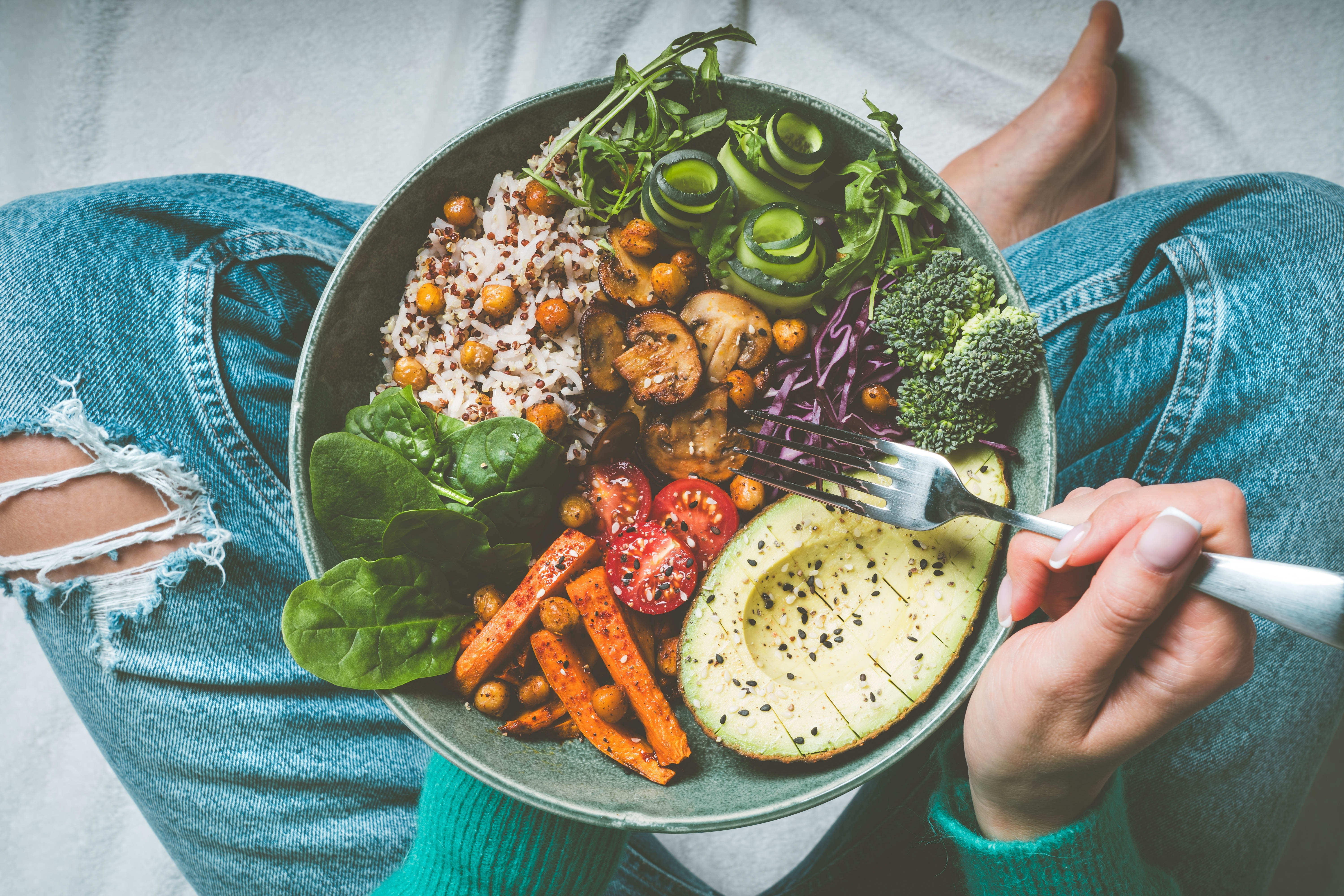 Woman sitting cross-legged with a big healthy salad on her lap